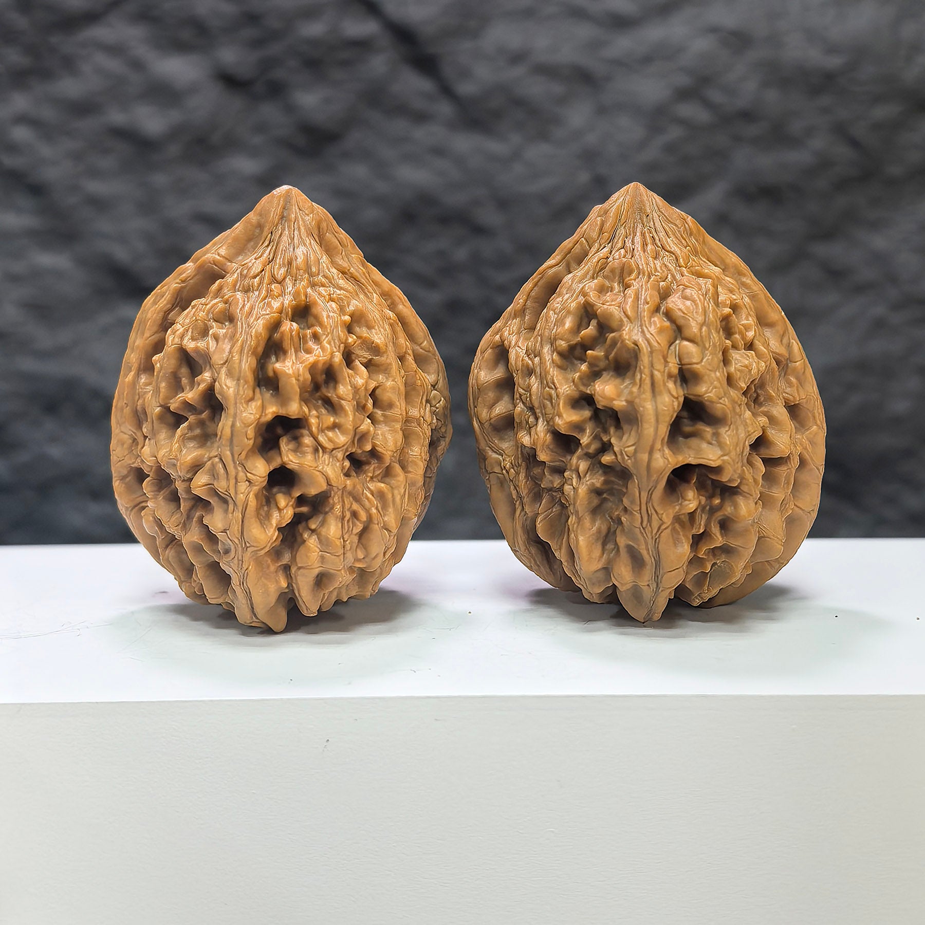 Pair of Dazhan Stone Wenwan walnuts by Wenwan Art, featuring smooth, polished surfaces and natural stone patterns, measuring 42x46mm.