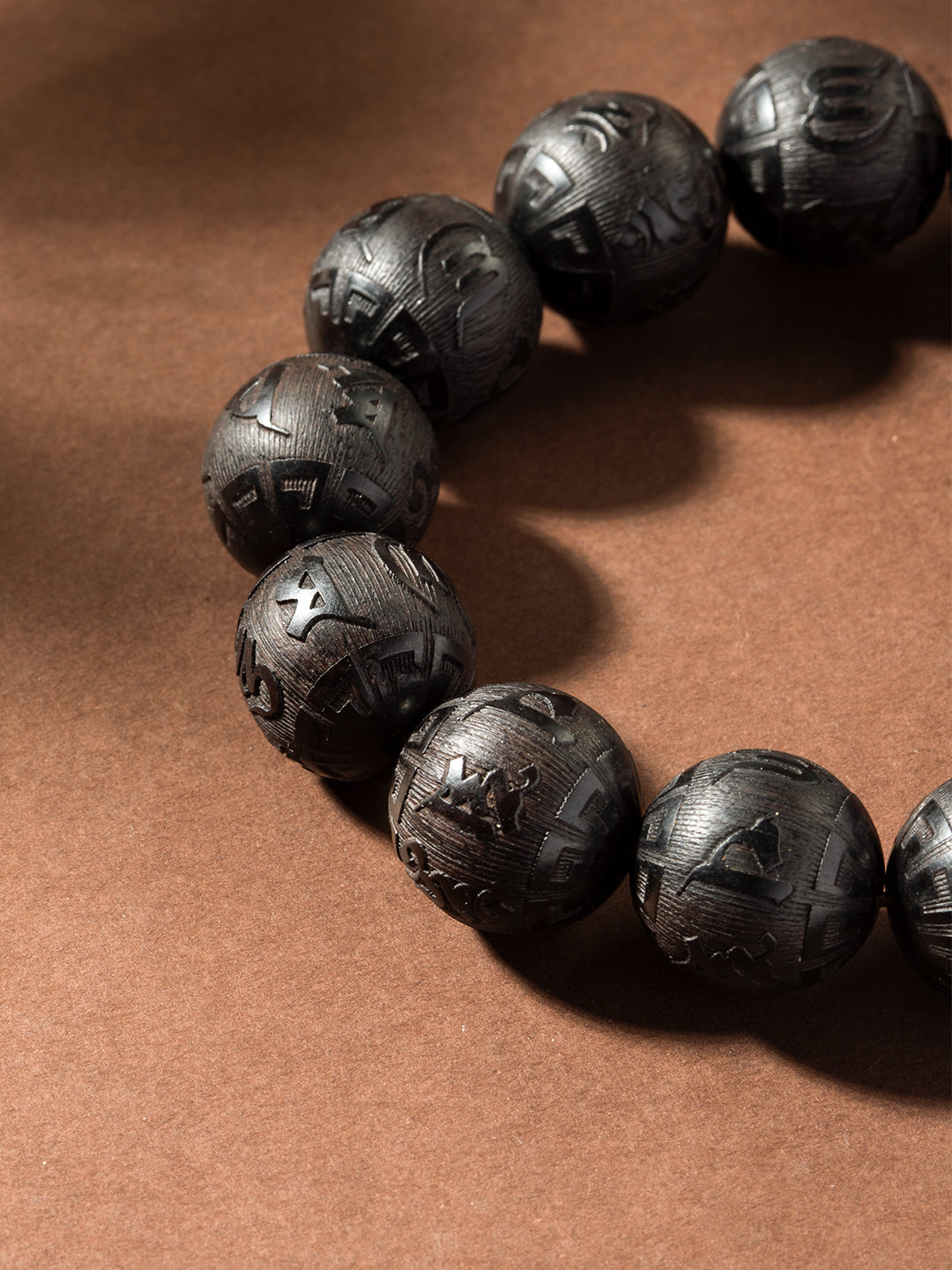 Carved ebony wood Om Mani Padme Hum bracelet with 16mm beads, featuring traditional blessing symbols and intricate craftsmanship.