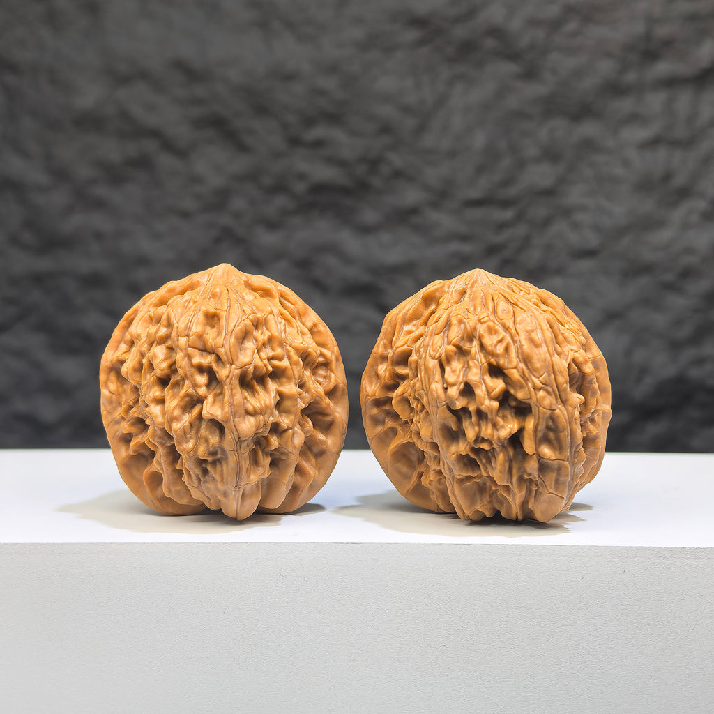 Pair of Wenwan Art Millstone Wenwan walnuts, 38mm x 37mm, featuring intricate carvings and natural wood grain.