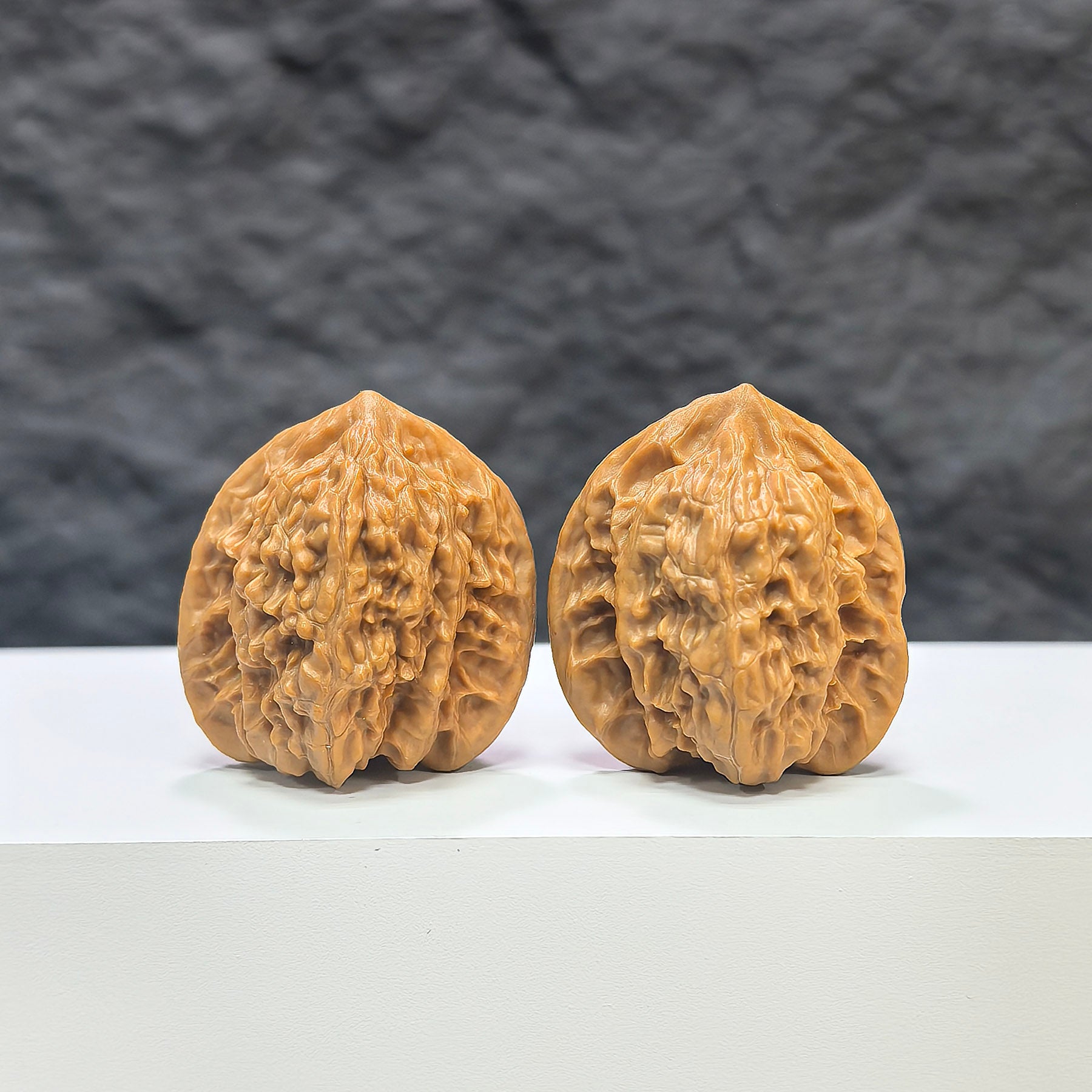 Pair of Xiayunling Pocket Wenwan Walnuts from Wenwan Art, miniature 32mm x 31mm natural walnut carvings on a white background.