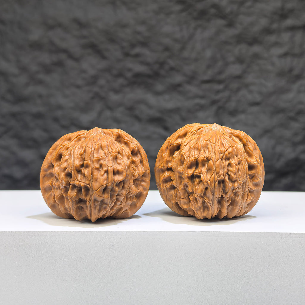 Pair of Wenwan Art Millstone Classic Wenwan Walnut carvings, 38mm x 34mm, featuring intricate wheel designs on smooth walnut surfaces.