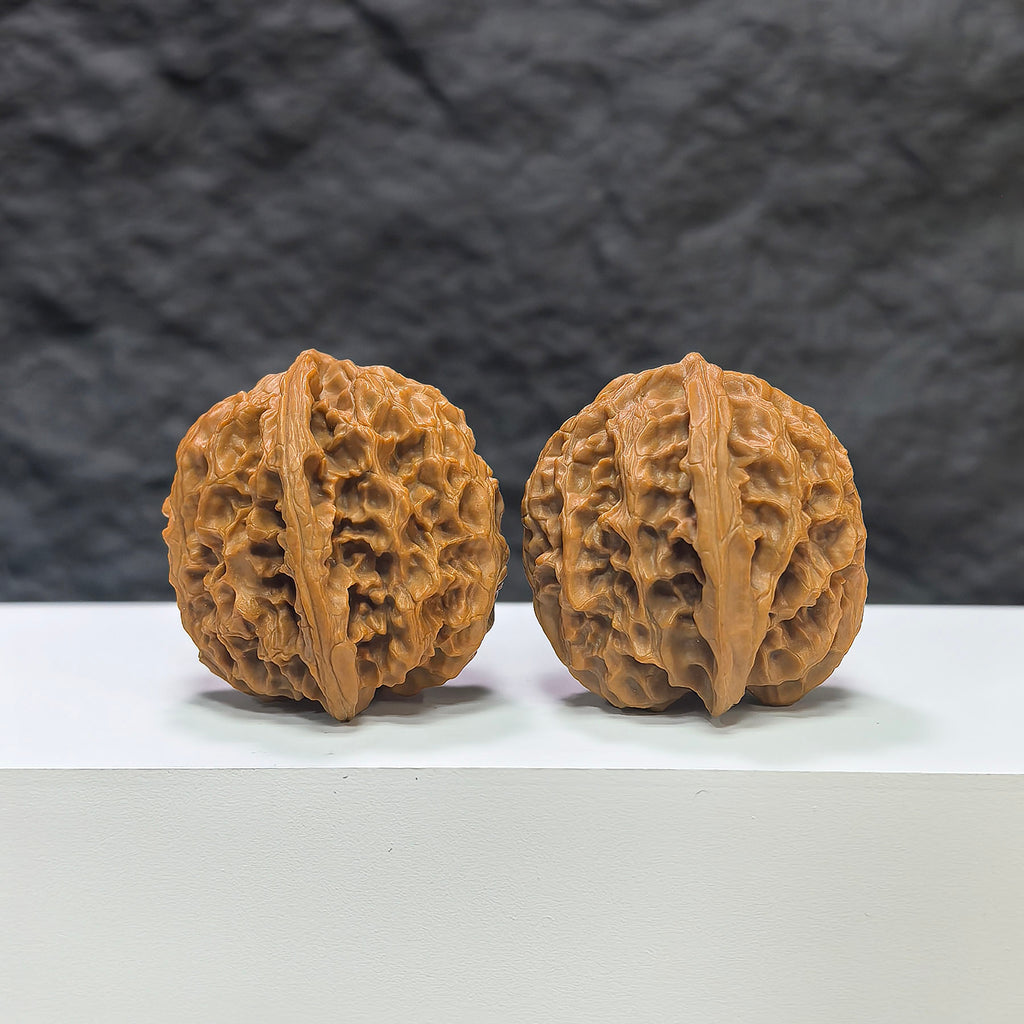 Pair of "Apple Garden" Wenwan walnuts by Wenwan Art, 36mm, featuring detailed carved designs on smooth, polished surfaces.