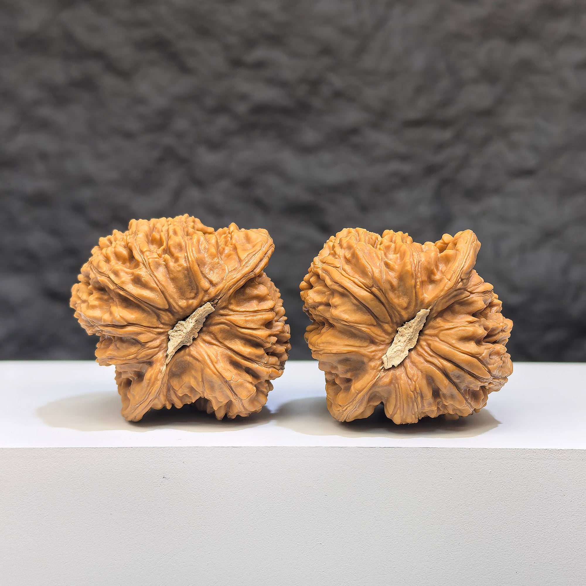 Pair of Wenwan Art "Ruby" Classic Wenwan Walnuts, 36mm, featuring red gemstone-like appearance and intricate carvings.